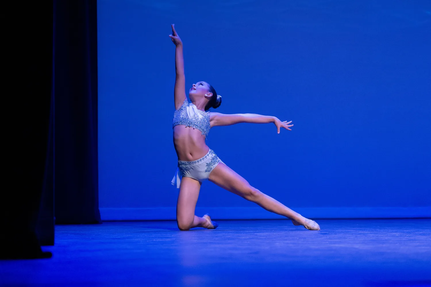 A dancer performing under blue stage lights.
